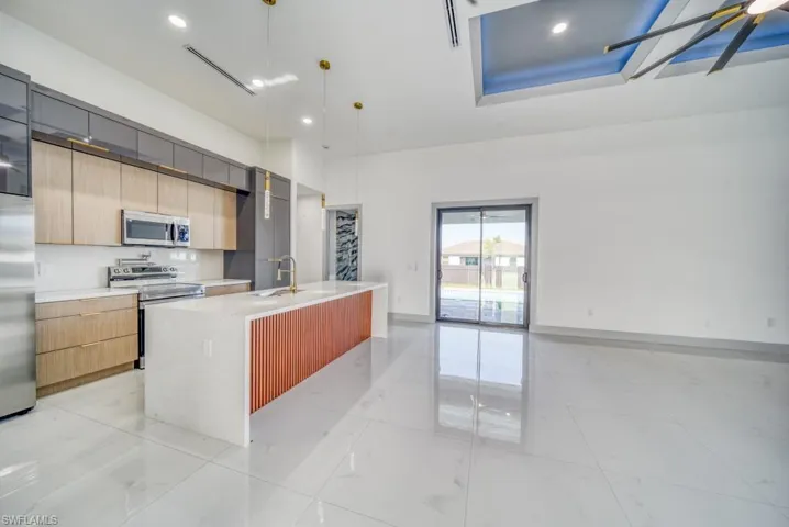 Kitchen with stainless steel appliances, modern cabinets, light countertops, a towering ceiling, and a sink