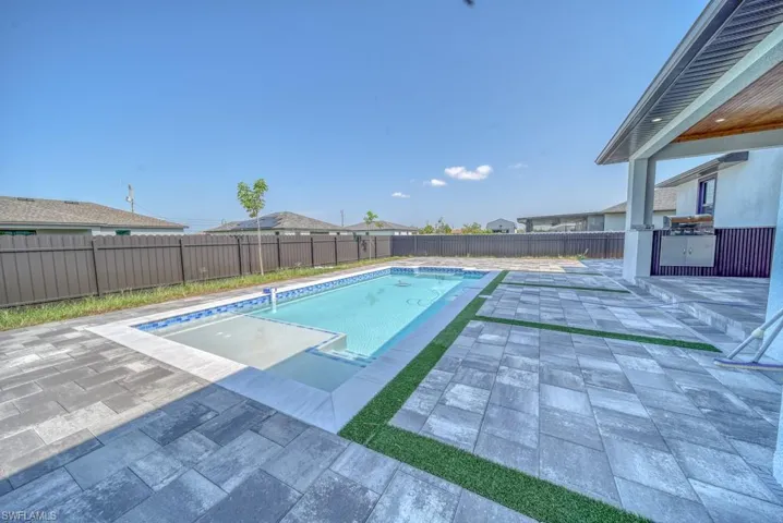 View of pool with a patio area, a fenced backyard, and an outdoor kitchen