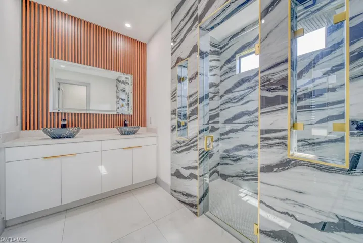 Bathroom featuring a marble finish shower, vanity, and recessed lighting