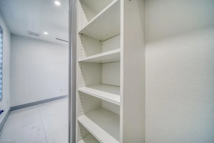 Spacious closet featuring light marble finish floors
