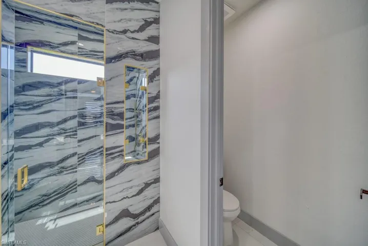 Full bathroom with toilet and a marble finish shower