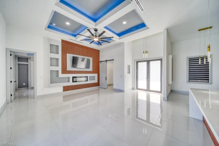 Unfurnished living room with coffered ceiling, baseboards, a ceiling fan, a barn door, and recessed lighting