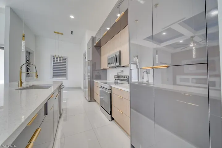 Kitchen with stainless steel appliances, modern cabinets, a sink, recessed lighting, and light stone counters