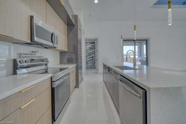 Kitchen with stainless steel appliances, modern cabinets, light brown cabinets, and a sink
