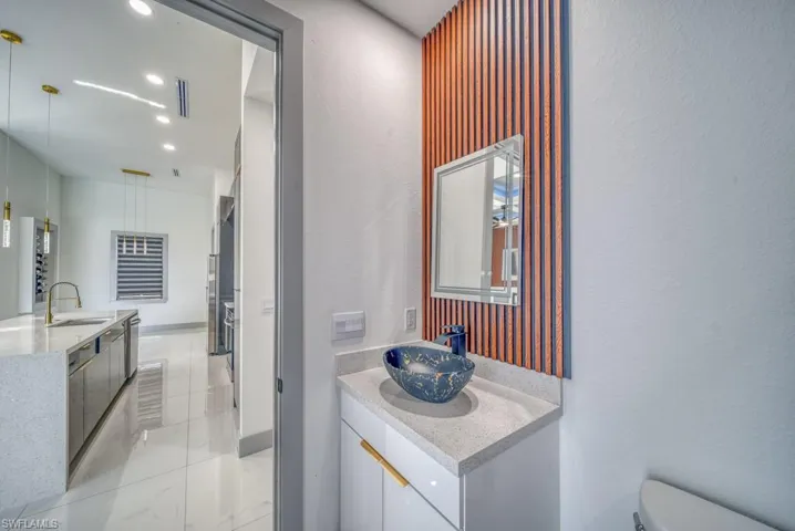 Bathroom featuring vanity, toilet, a textured wall, recessed lighting, and marble finish flooring