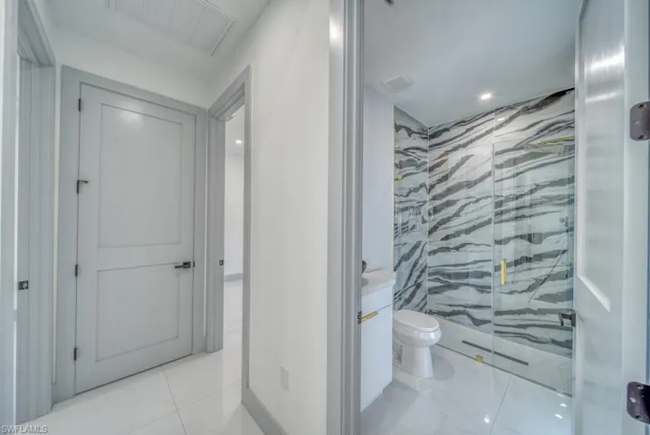 Bathroom with a marble finish shower, toilet, and vanity
