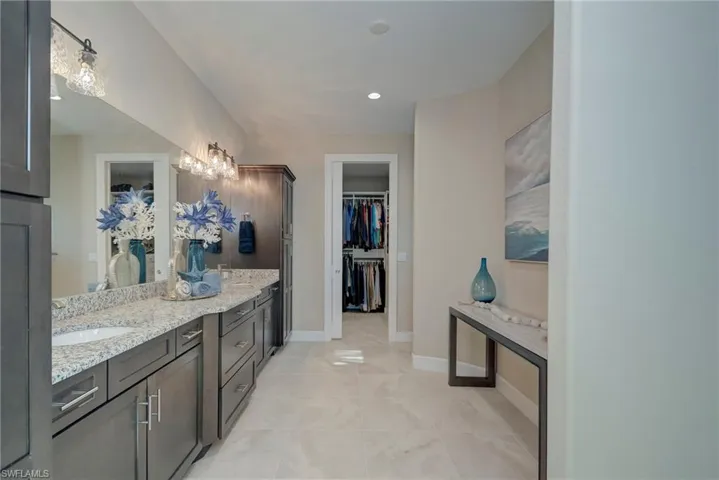 Bathroom with a spacious closet, vanity, light tile patterned floors, and recessed lighting