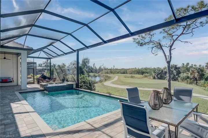 View of swimming pool with a sunroom, a lanai, a pool with connected hot tub, a yard, and a patio