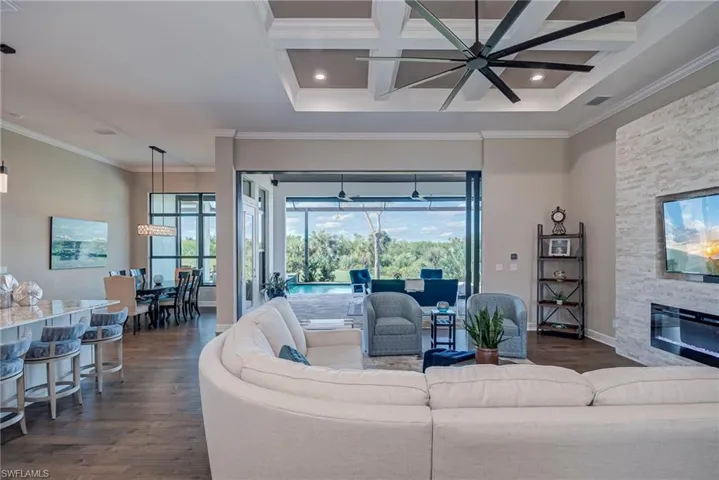 Living room featuring dark wood-style flooring, coffered ceiling, ornamental molding, a sunroom, and beam ceiling