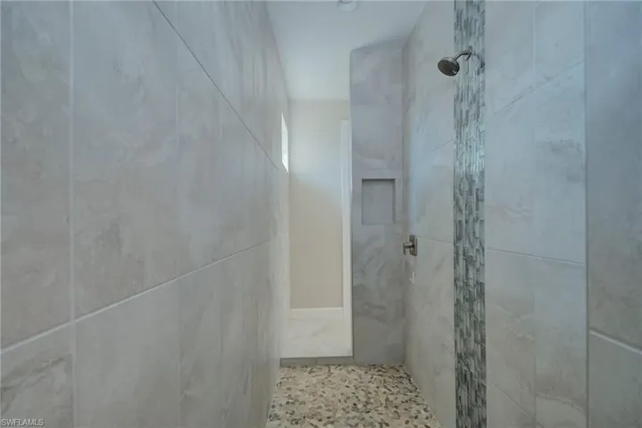Bathroom featuring a tile shower and tile walls