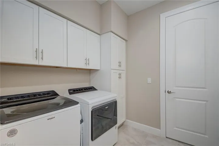 Washroom with cabinet space, washer and dryer, and light tile patterned floors