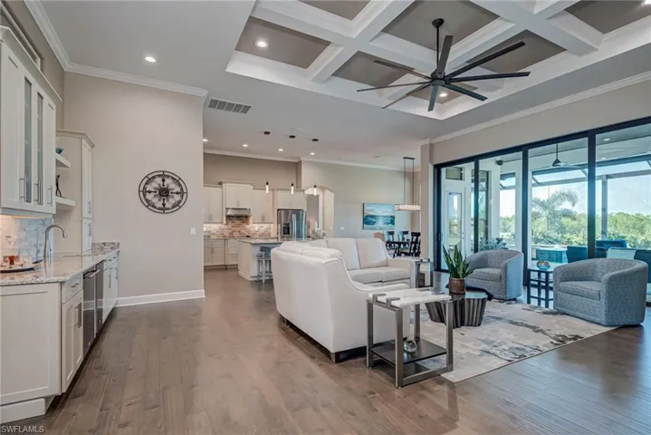 Living area with ornamental molding, recessed lighting, coffered ceiling, dark wood-type flooring, and a ceiling fan
