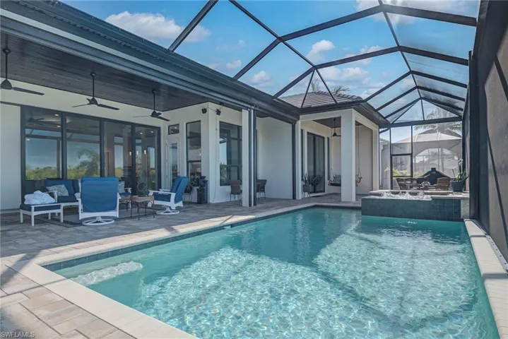 View of swimming pool featuring a ceiling fan, a sunroom, an outdoor hangout area, a patio area, and glass enclosure