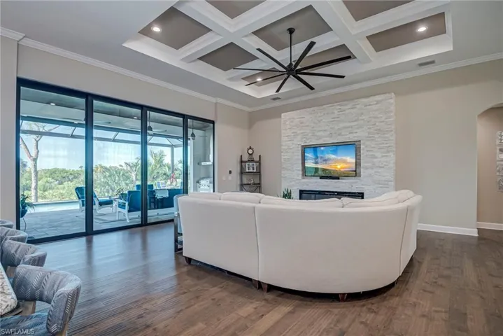 Living area with ornamental molding, a fireplace, dark wood-style floors, arched walkways, and ceiling fan