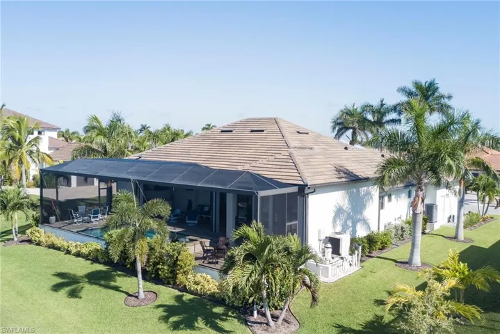 Back of house with a lawn, a lanai, a sunroom, stucco siding, and a tile roof