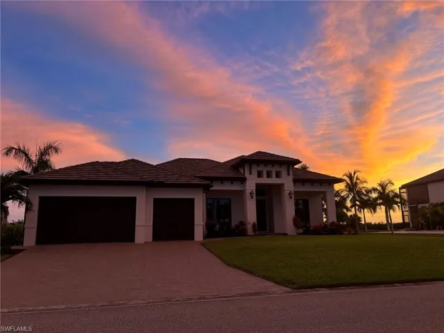 View of front of house with an attached garage, a front yard, decorative driveway, stucco siding, and a tiled roof