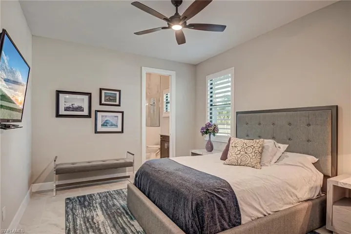 Bedroom with ceiling fan, connected bathroom, and light tile patterned floors