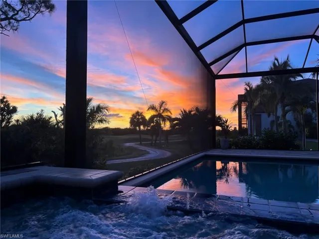 Pool at dusk featuring an outdoor pool, a lanai, and a sunroom
