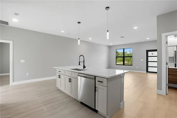 Kitchen featuring hanging light fixtures, an island with sink, dishwasher, open floor plan, and recessed lighting