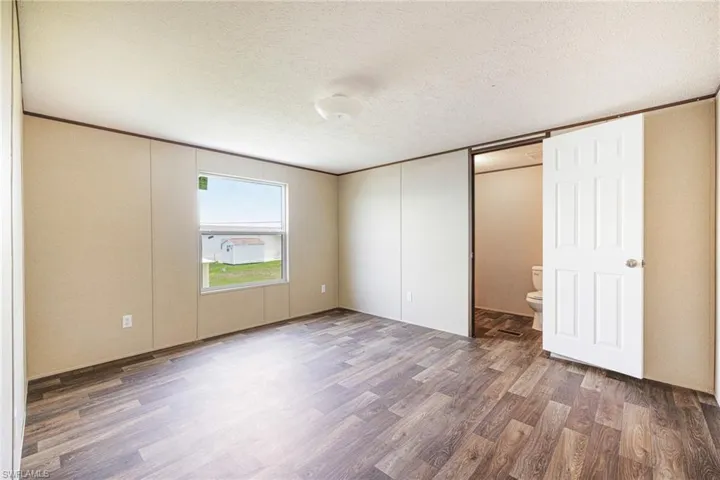 Unfurnished bedroom with wood finished floors, a textured ceiling, and connected bathroom