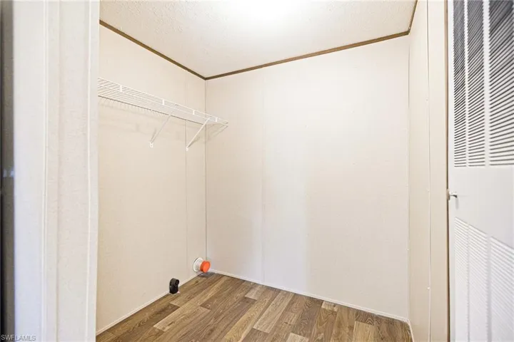 Laundry room with wood finished floors and ornamental molding