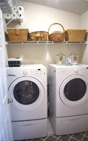 Laundry room with washer and clothes dryer and light tile patterned floors