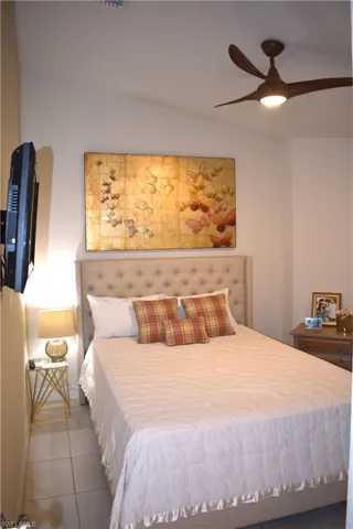 Bedroom featuring light tile patterned floors, vaulted ceiling, and ceiling fan