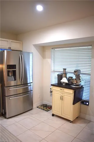 Kitchen featuring light tile patterned floors and stainless steel fridge with ice dispenser