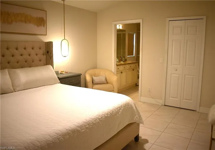 Bedroom with vaulted ceiling, light tile patterned flooring, and ensuite bathroom