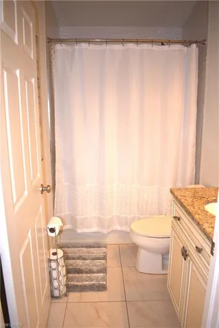 Full bathroom featuring shower / bath combo, vanity, toilet, and tile patterned floors