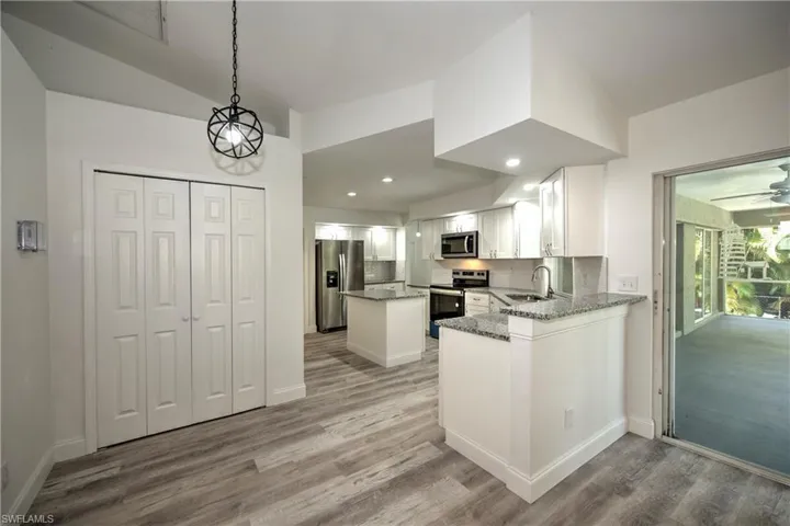 Kitchen with light stone countertops, a sink, stainless steel appliances, light wood-type flooring, and white cabinetry