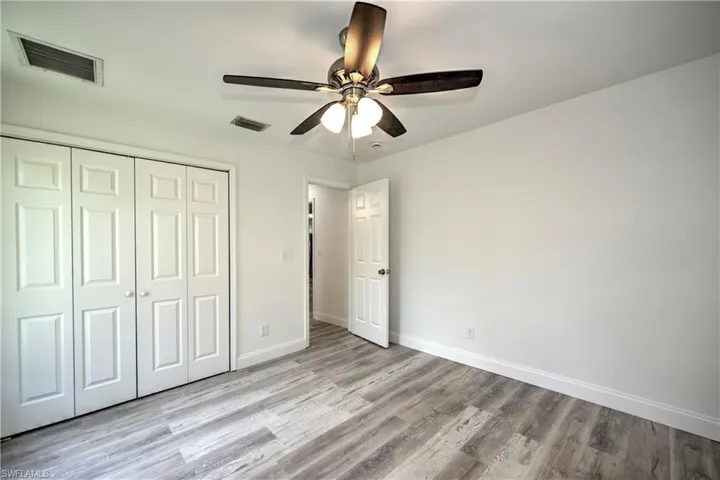 Unfurnished bedroom featuring wood finished floors, visible vents, baseboards, and a closet