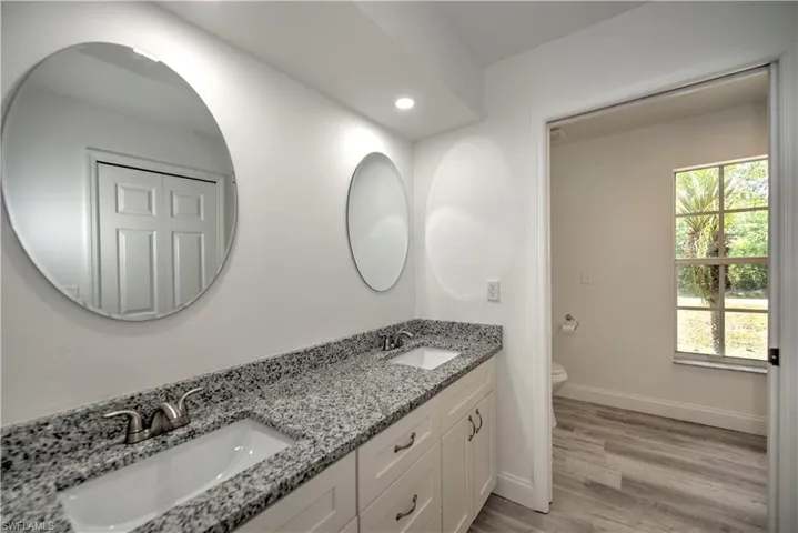 Full bathroom with wood finished floors, toilet, baseboards, and a sink