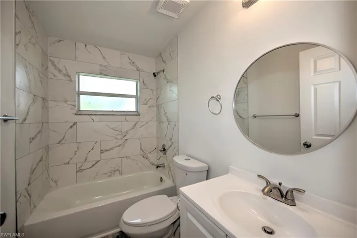 Bathroom with toilet, visible vents, washtub / shower combination, and vanity