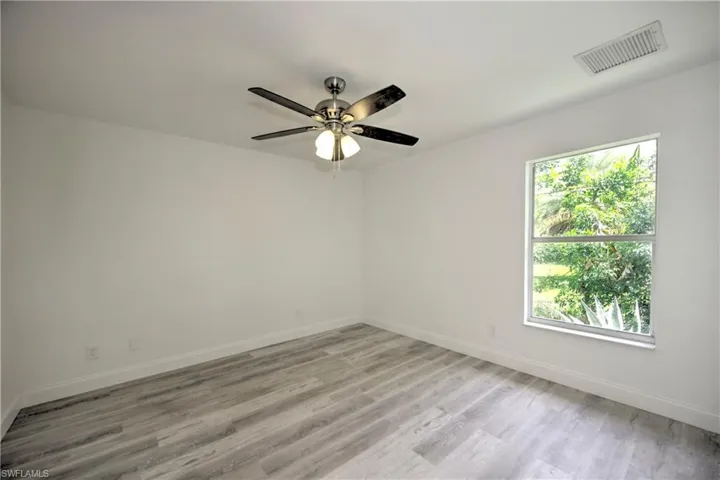 Unfurnished room with light wood finished floors, visible vents, and plenty of natural light