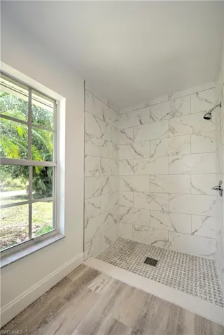 Bathroom with baseboards, a wealth of natural light, and a tile shower