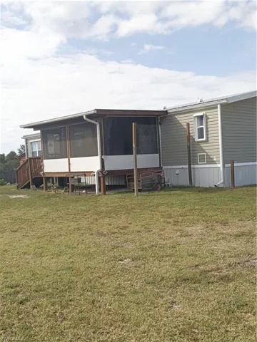 Back of house with a sunroom and a lawn