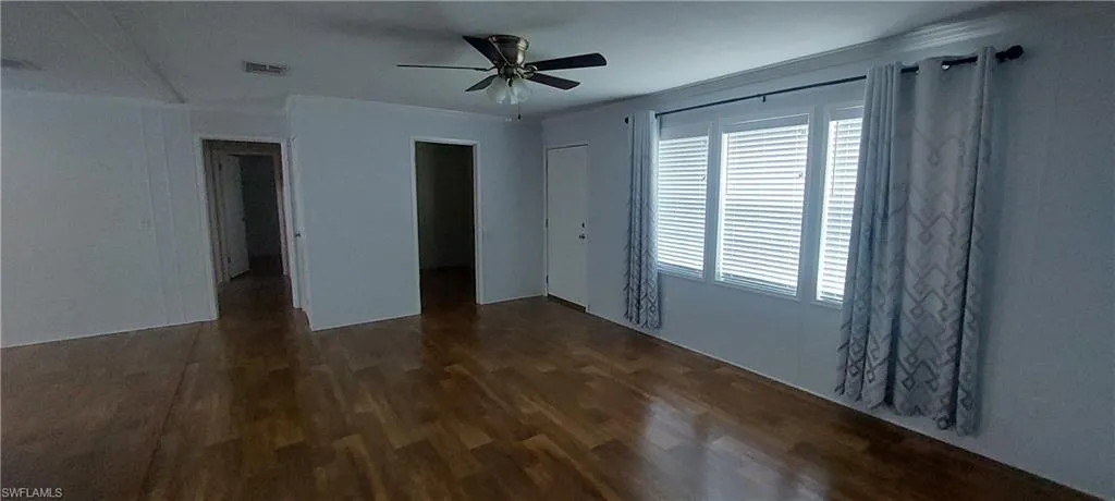 Livingroom with dark wood finished floors, and a ceiling fan. 9x9 office space off the livingroom