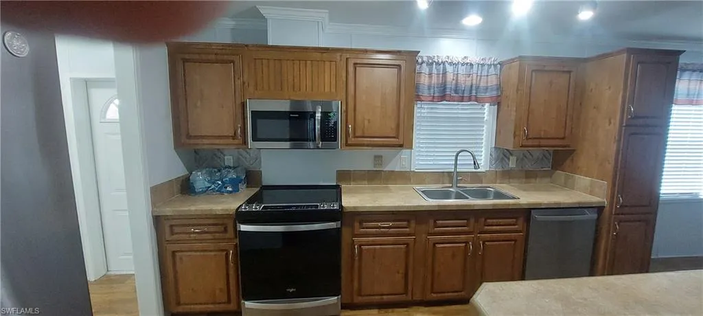 Kitchen with stainless appliances, light countertops, and brown cabinets