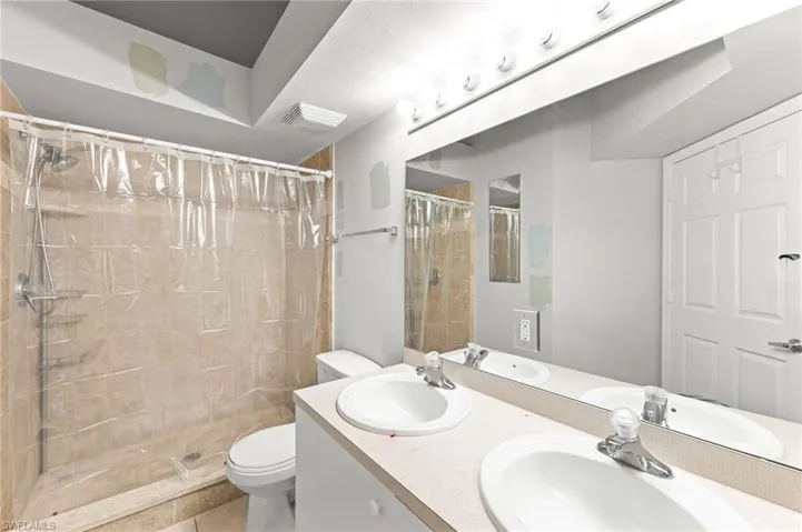 Bathroom featuring double vanity, a stall shower, and tile patterned flooring