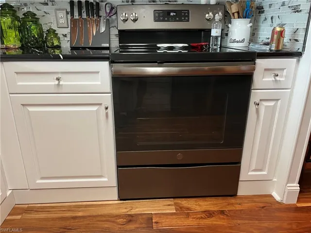 Interior details with white cabinets, electric range, and tasteful backsplash
