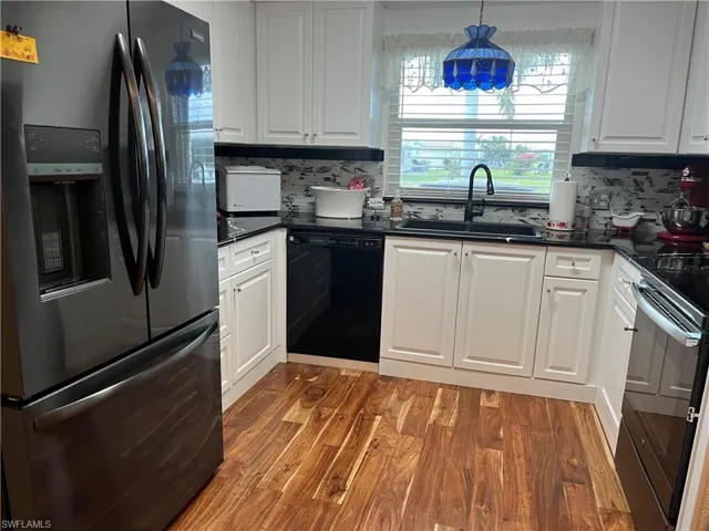 Kitchen featuring hanging light fixtures, white cabinetry, sink, and black appliances