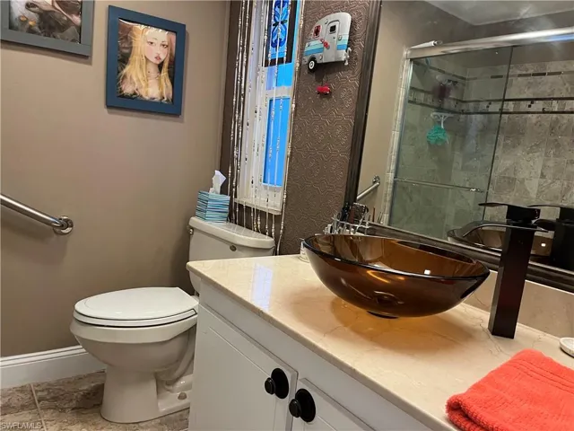 Bathroom featuring walk in shower, tile patterned flooring, vanity, and toilet