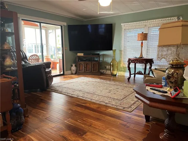Living room featuring ceiling fan, ornamental molding, vaulted ceiling, and hardwood / wood-style flooring