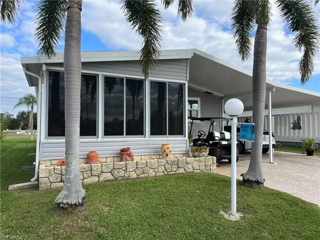 Back of house featuring a yard, a carport, and a sunroom