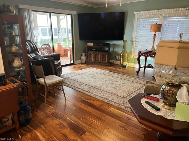 Living room with wood-type flooring and crown molding