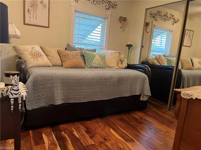 Bedroom with multiple windows, a closet, and dark hardwood / wood-style floors