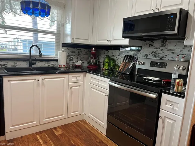 Kitchen featuring white cabinets, decorative backsplash, sink, and stainless steel appliances