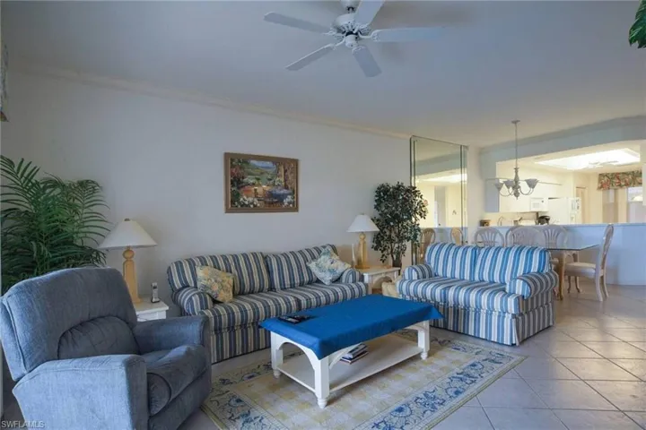 Tiled living room with ceiling fan with notable chandelier and ornamental molding