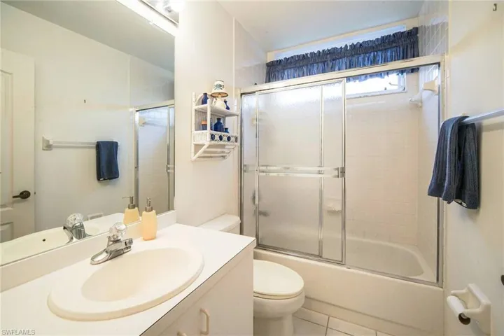 Full bathroom with tile patterned flooring, vanity, toilet, and bath / shower combo with glass door